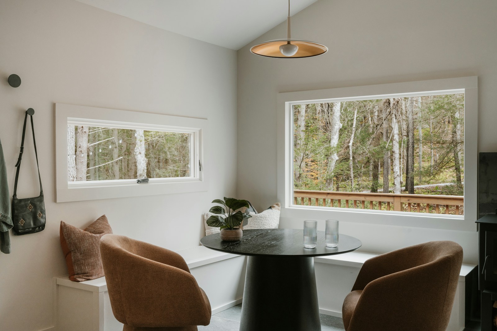 Corner window banquette with cushions and a round pedestal table, two armchairs opposite