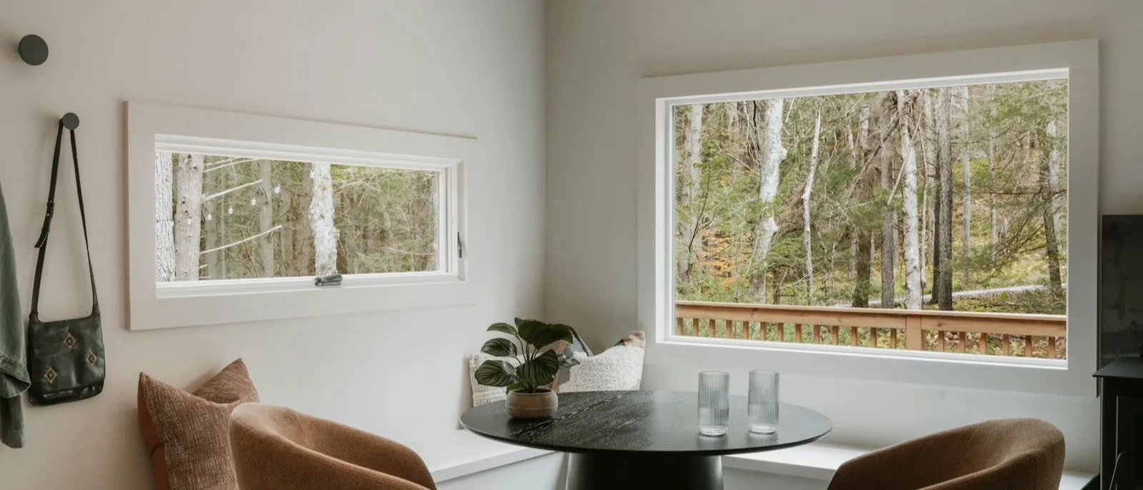 Corner window banquette with cushions and a round pedestal table, two armchairs opposite