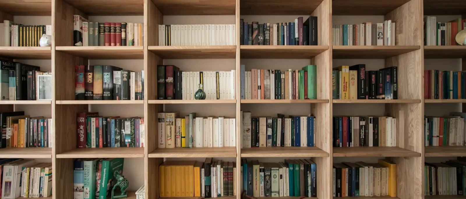 Wall-to-wall oak built-in bookshelves filled with books, with a row of drawers across the bottom