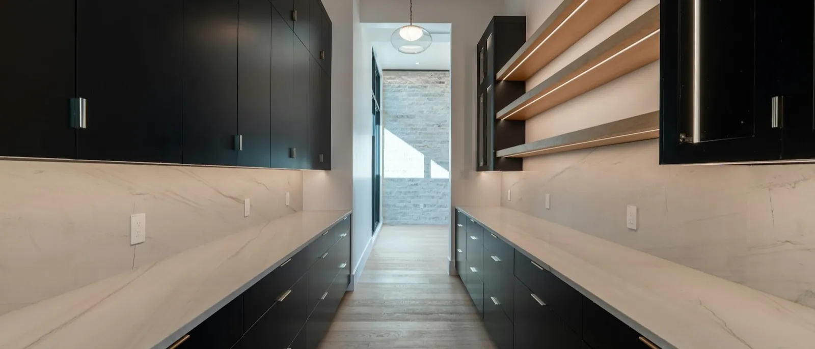 Galley butler's pantry with black cabinets, white stone counters, and a clear center walkway