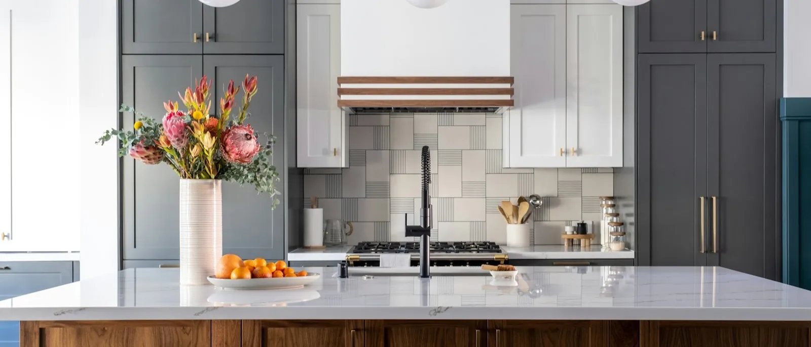 Two-tone kitchen with charcoal floor-to-ceiling cabinets, white uppers, a patterned tile backsplash, and a walnut island