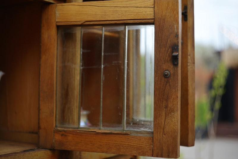 Close-up of a glazed wooden cabinet door standing open on its latch