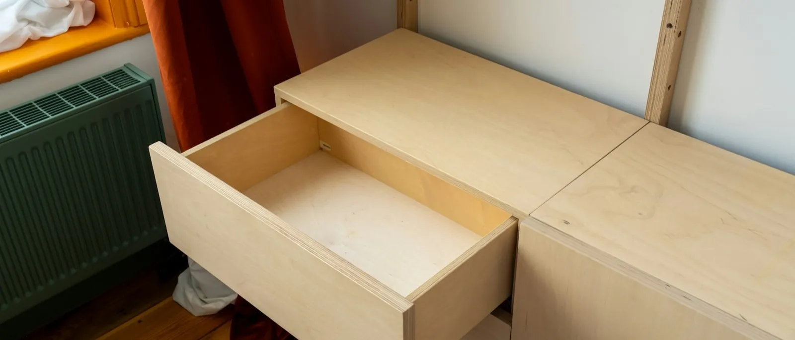 Open birch plywood drawer in a wall-hung cabinet, with the plywood edge layers visible