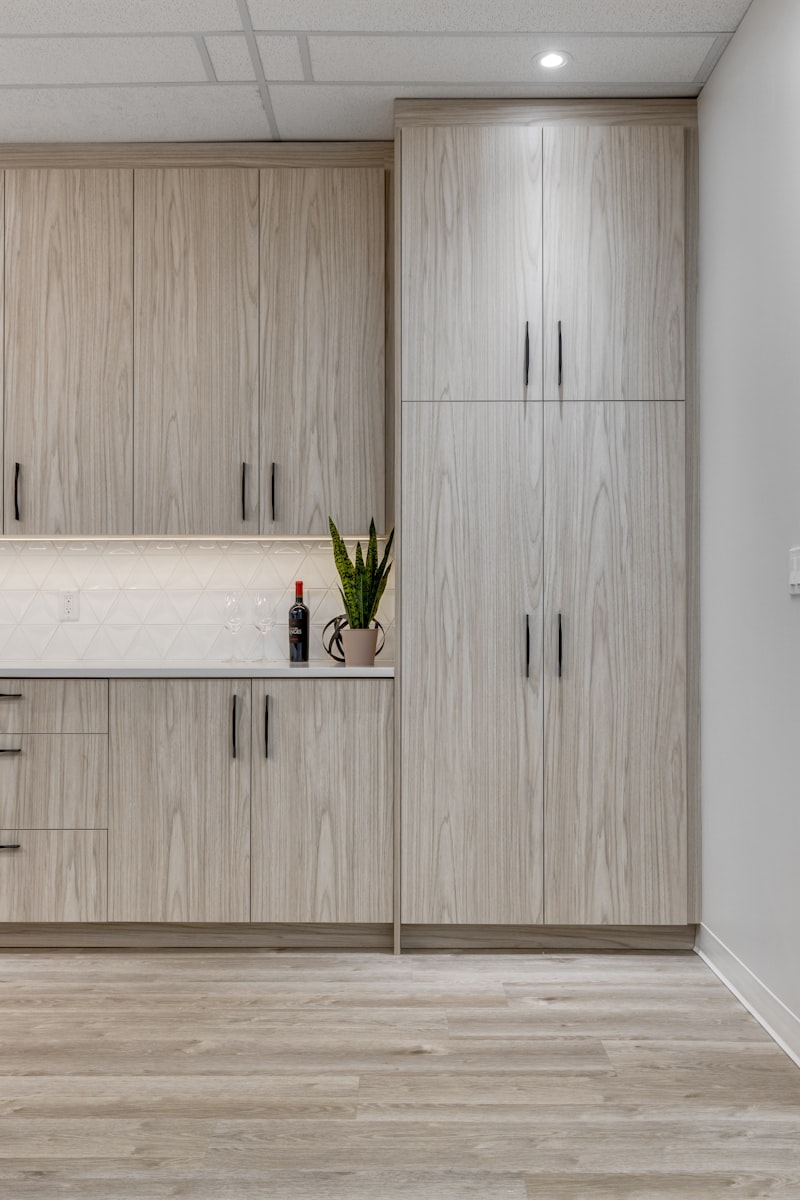 Pale wood-grain cabinets running floor to ceiling beside a white counter and tiled backsplash